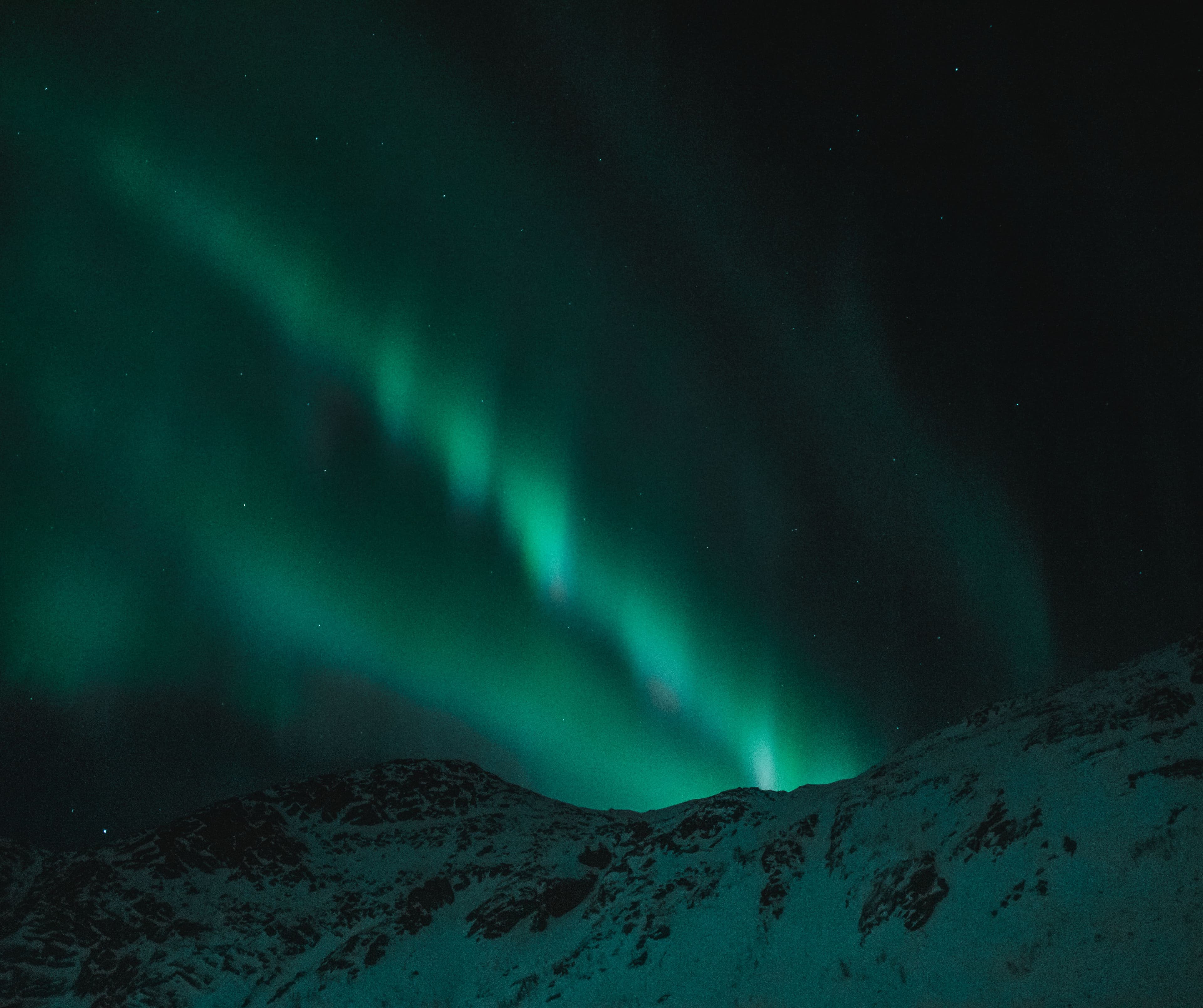 Aurora borealis above snow-covered mountains under a night sky